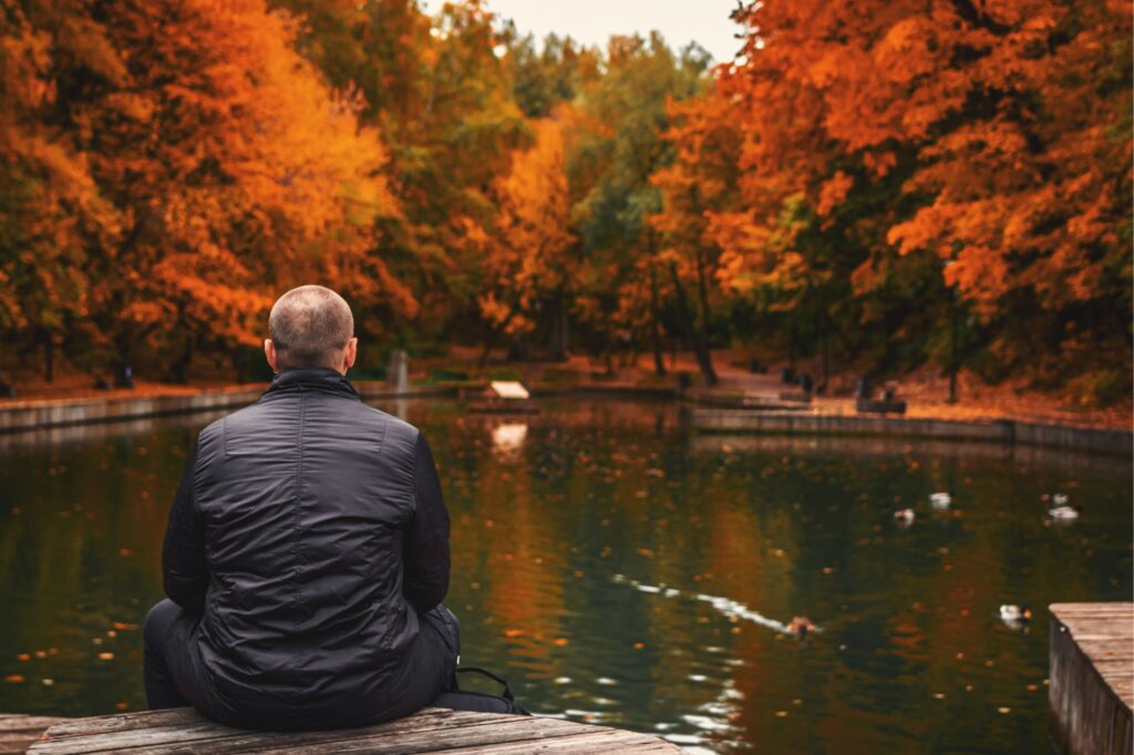 Alone man sits beside a pond